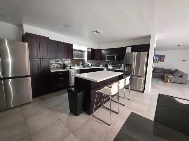 a kitchen with stainless steel appliances a refrigerator a sink a stove a microwave and a refrigerator