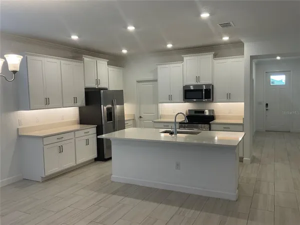 a kitchen with kitchen island a white counter top space stainless steel appliances and cabinets