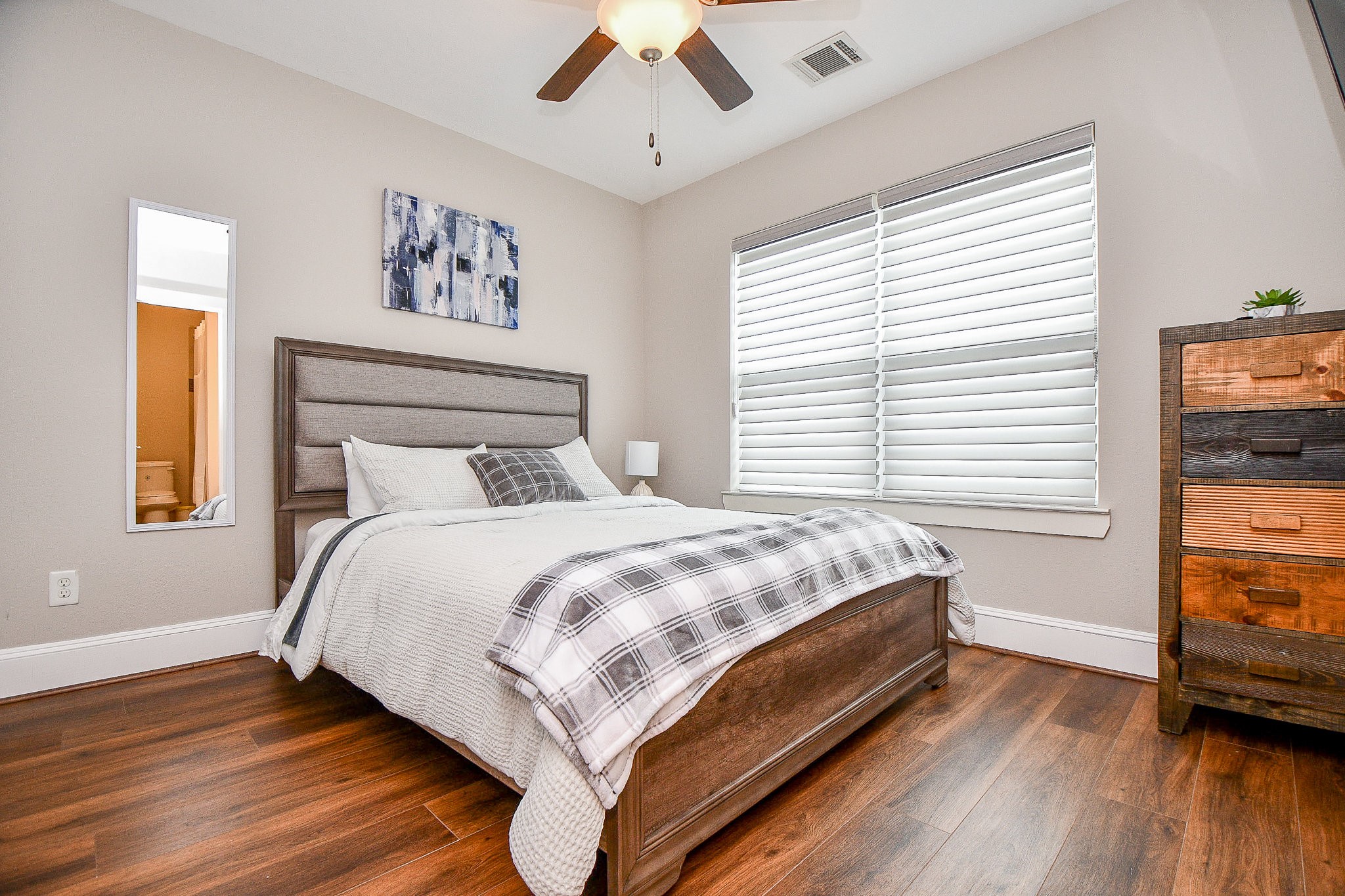 4604 Chartres Street Houston, TX 77004 - Photo 14 of 20 Bright, warm, and beautifully finished, this secondary bedroom features rich hardwood floors, generous natural
light, and a serene neutral palette that offers a restful and inviting retreat for family or guests. A private
en-suite bath glimpsed through the doorway adds exceptional convenience.