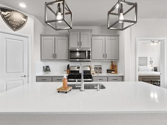 a kitchen with granite countertop a sink stainless steel appliances and white cabinets