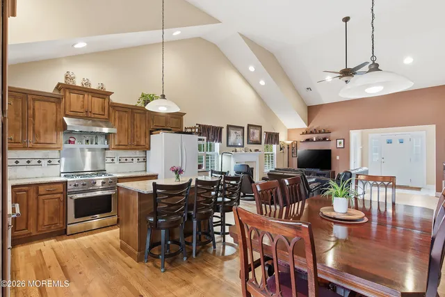 a view of kitchen with stainless steel appliances wooden floor dining table and chairs