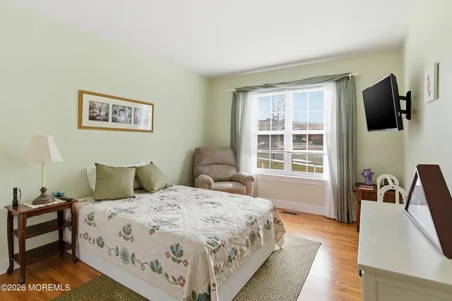a spacious bedroom with a bed and a flat tv screen on the dresser