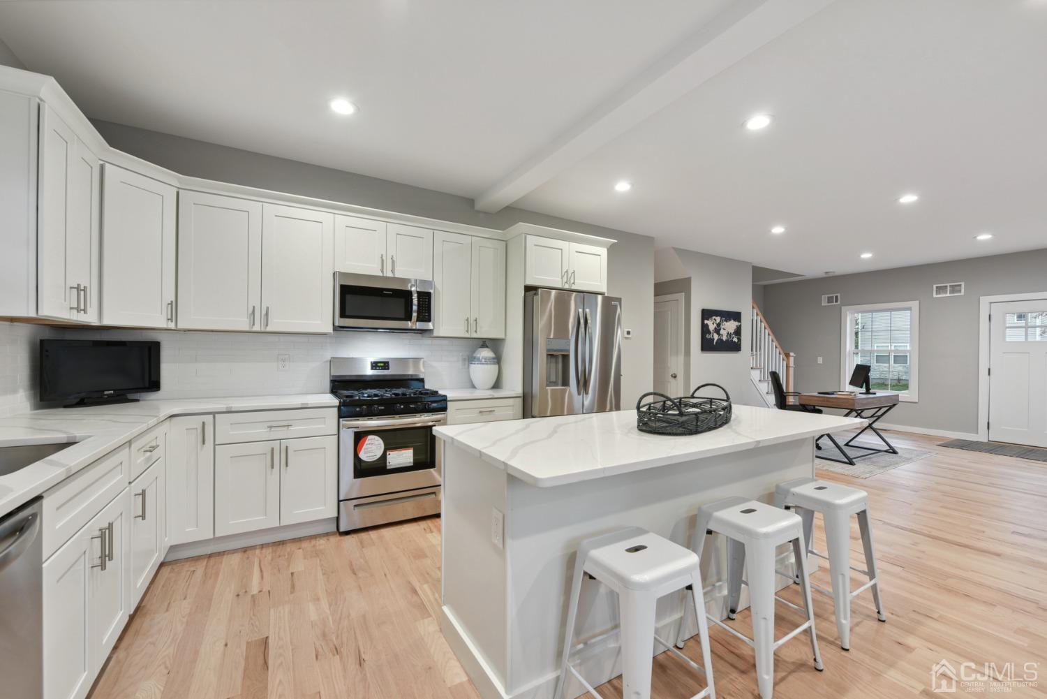13 Albany Street Edison, NJ 08837 - Photo 11 of 26 a kitchen with stainless steel appliances granite countertop a stove top oven a sink a refrigerator white cabinets and wooden floor