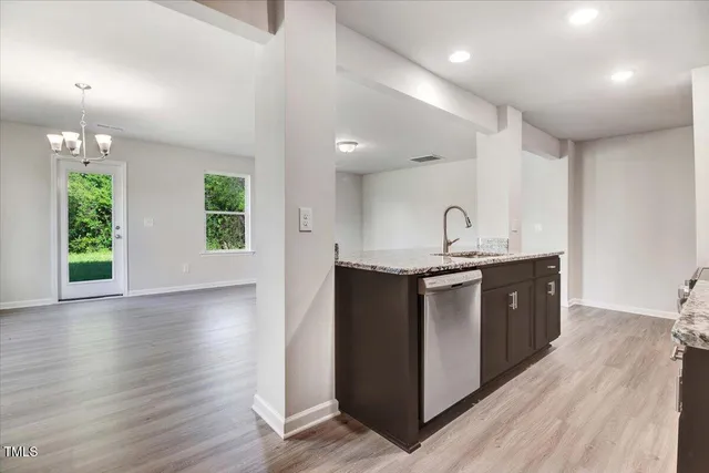 a kitchen with kitchen island granite countertop a sink cabinets and wooden floor
