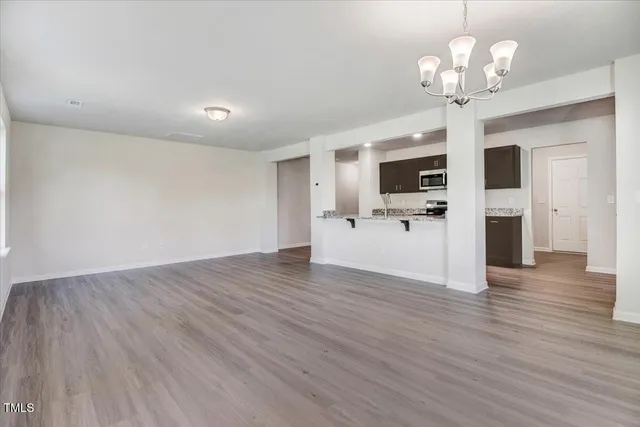 a view of a livingroom with a kitchen island wooden floor and a chandelier