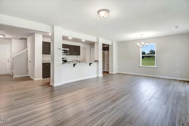 an empty space with wooden floor and a kitchen