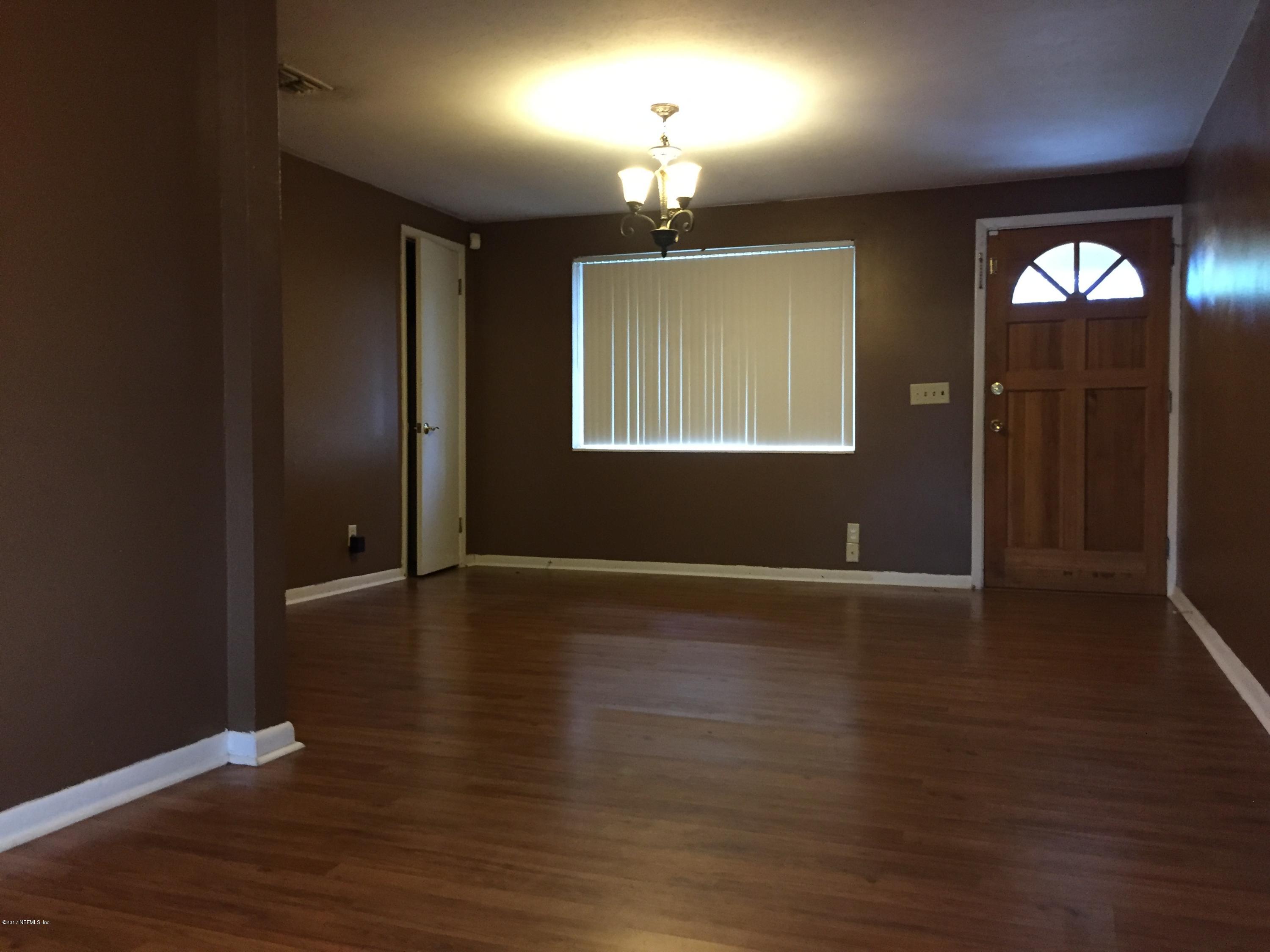 5838 Ensenada Road Jacksonville, FL 32244 - Photo 4 of 23 an empty room with wooden floor chandelier and windows