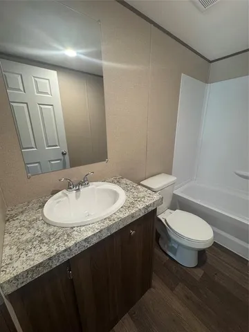 a bathroom with a granite countertop toilet a sink and a mirror