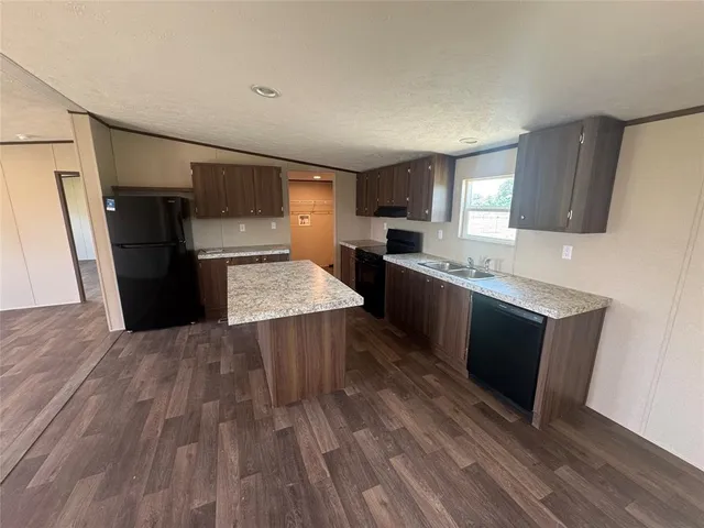 a kitchen with granite countertop a refrigerator a stove top oven a sink and dishwasher