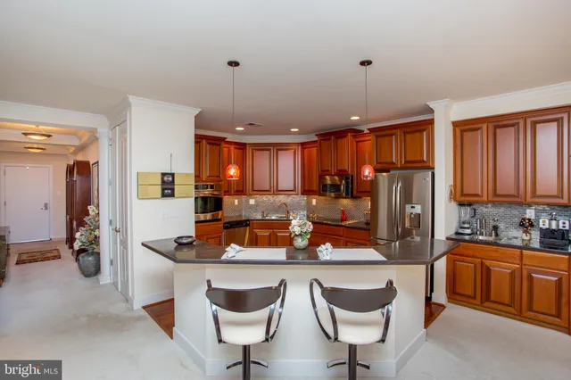 a kitchen with stainless steel appliances granite countertop a refrigerator a sink dishwasher and wooden cabinets with wooden floor