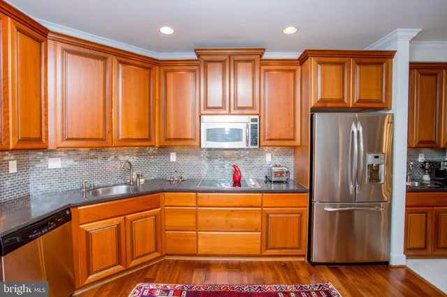 a kitchen with stainless steel appliances granite countertop a sink a stove and cabinets