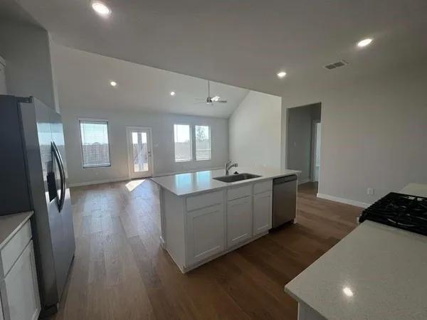 a large kitchen with stainless steel appliances granite countertop a large counter top a sink and a refrigerator