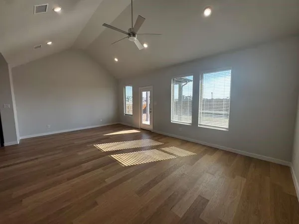 an empty room with wooden floor and windows