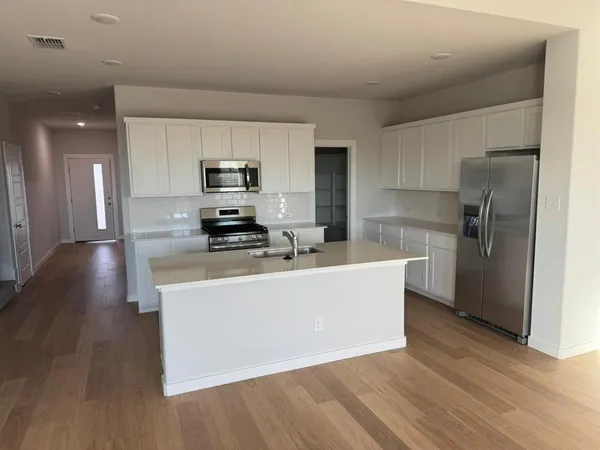 a living room with stainless steel appliances a refrigerator a stove a microwave and wooden floor