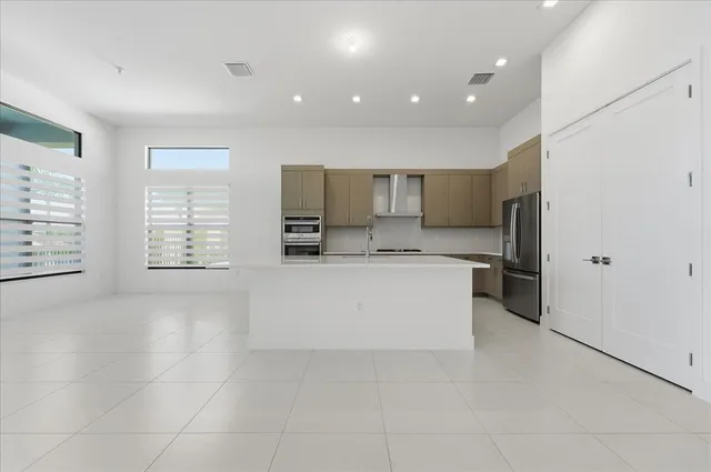 a large white kitchen with kitchen island a counter top a sink a stove a refrigerator and a window