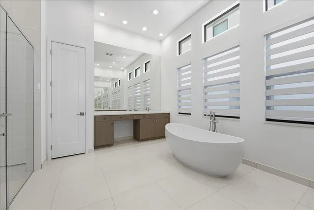 a spacious bathroom with a tub a double vanity sink a mirror and a shower