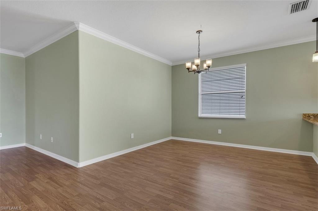 2391 Heydon Circle East Naples, FL 34120 - Photo 12 of 42 an empty room with wooden floor chandelier and windows