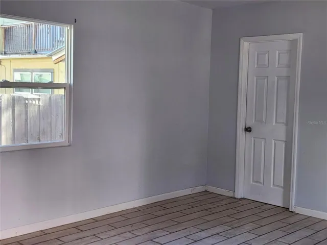 a view of an empty room with wooden floor and a window