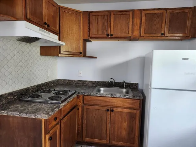 a kitchen with granite countertop a sink stove and cabinets