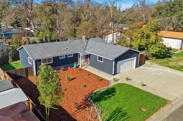 an aerial view of a house with yard and trees in the background
