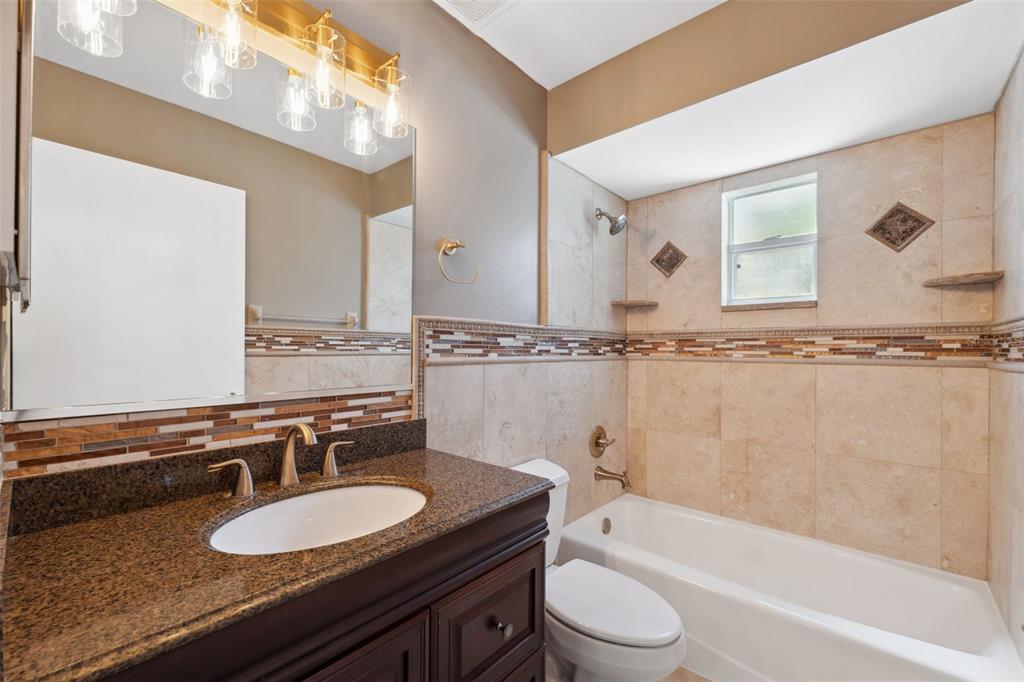 428 West Klosterman Road Palm Harbor, FL 34683 - Photo 24 of 44 a bathroom with a granite countertop sink mirror toilet and bathtub