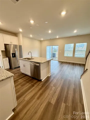 a living room with stainless steel appliances kitchen island granite countertop wooden floors and sink