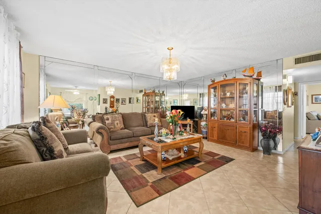 a living room with furniture kitchen view and a chandelier