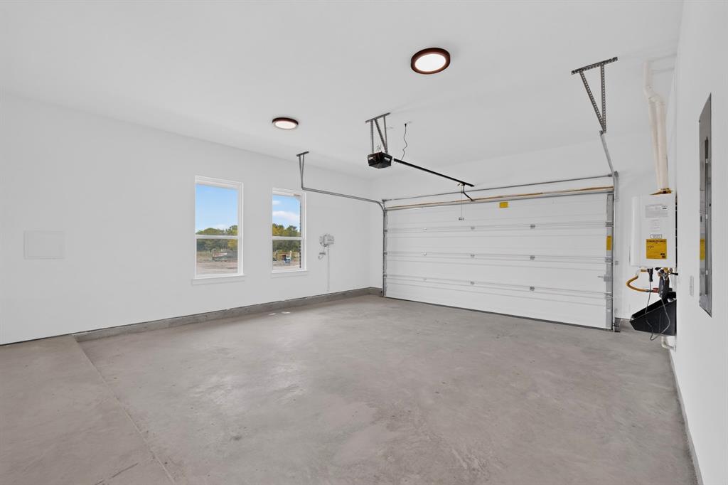 5410 Sunset Road Caddo Mills, TX 75135 - Photo 37 of 40 Concrete flooring, two windows, two ceiling-mounted light fixtures, garage door, and a wall-mounted water heater