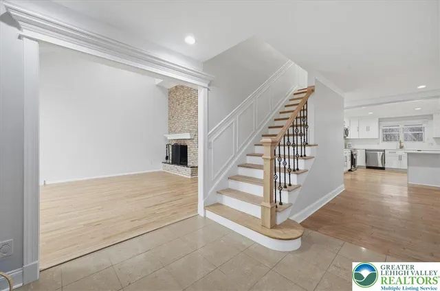 a view of an empty room with wooden floor fireplace and a window