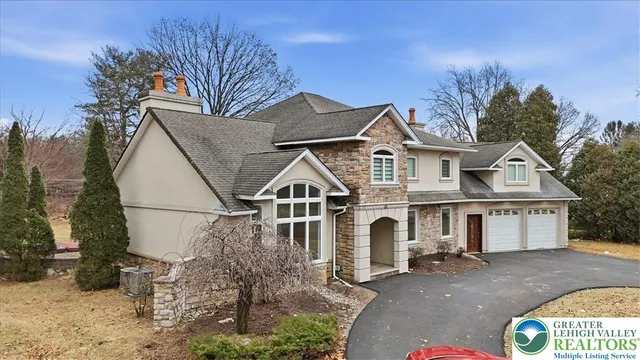 a view of a white house with a large tree and plants