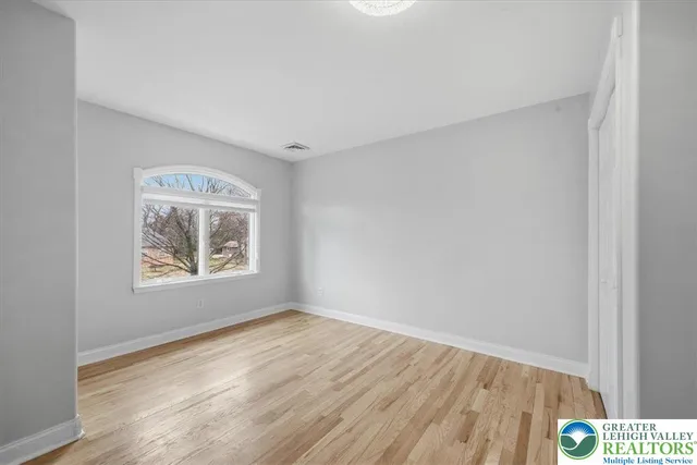 a view of empty room with window and wooden floor