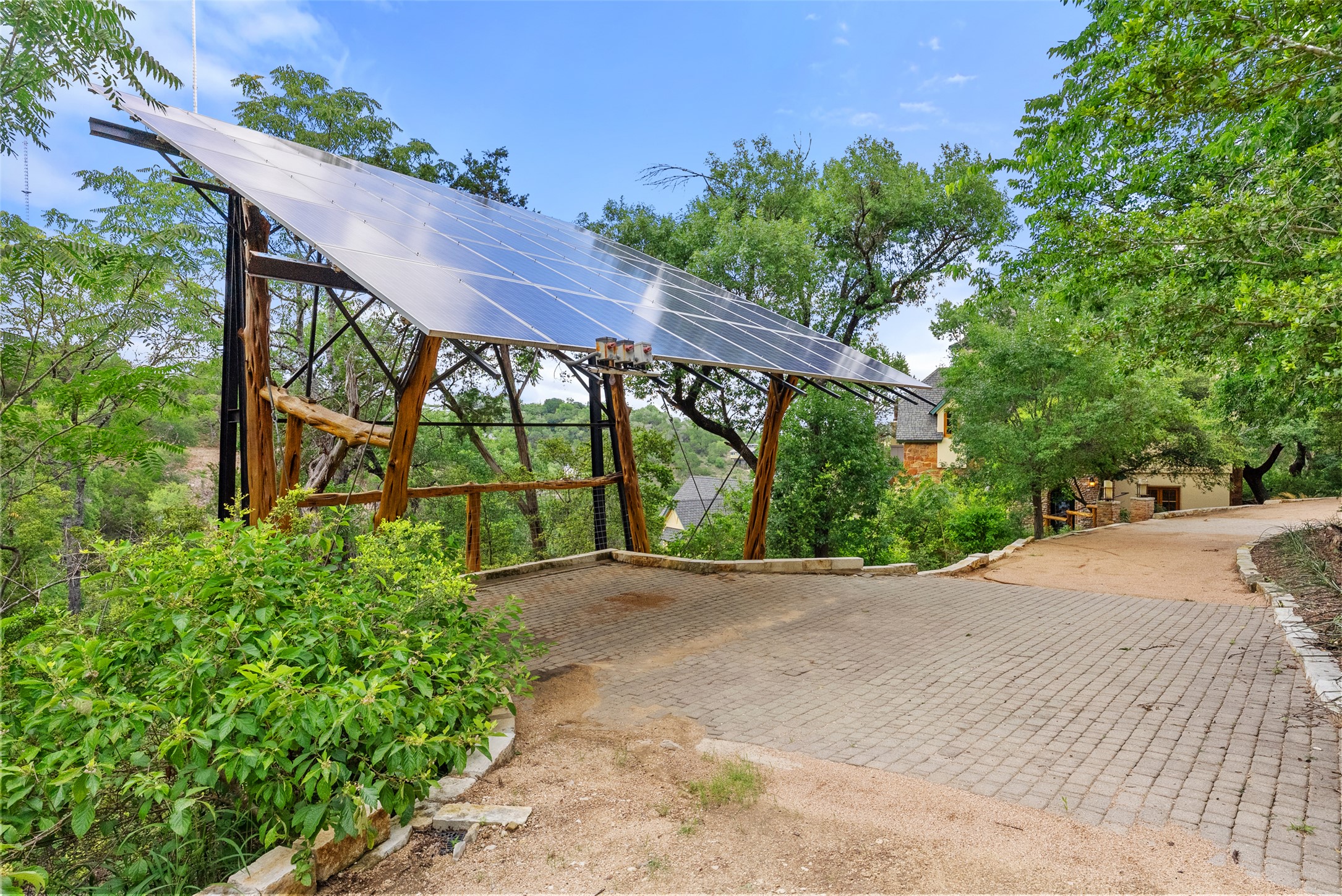 1354 The High Road Austin, TX 78746 - Photo 38 of 40 A spacious brick paver driveway with a solar panel carport offers ample parking and eco-friendly power.