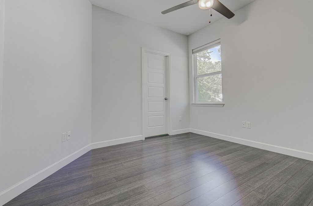 2406 East 16th Street Austin, TX 78702 - Photo 10 of 39 an empty room with wooden floor chandelier fan and windows