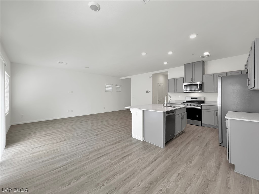 9984 Indigo Cliffs Street Las Vegas, NV 89141 - Photo 29 of 31 Kitchen featuring gray cabinetry, an island with sink, a sink, open floor plan, and appliances with stainless steel finishes