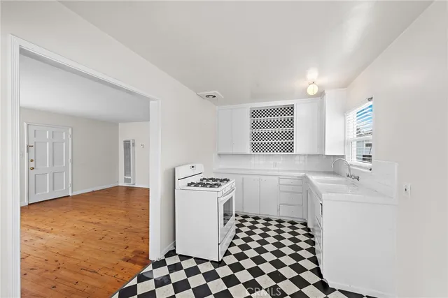 a kitchen with a sink a stove cabinets and wooden floor