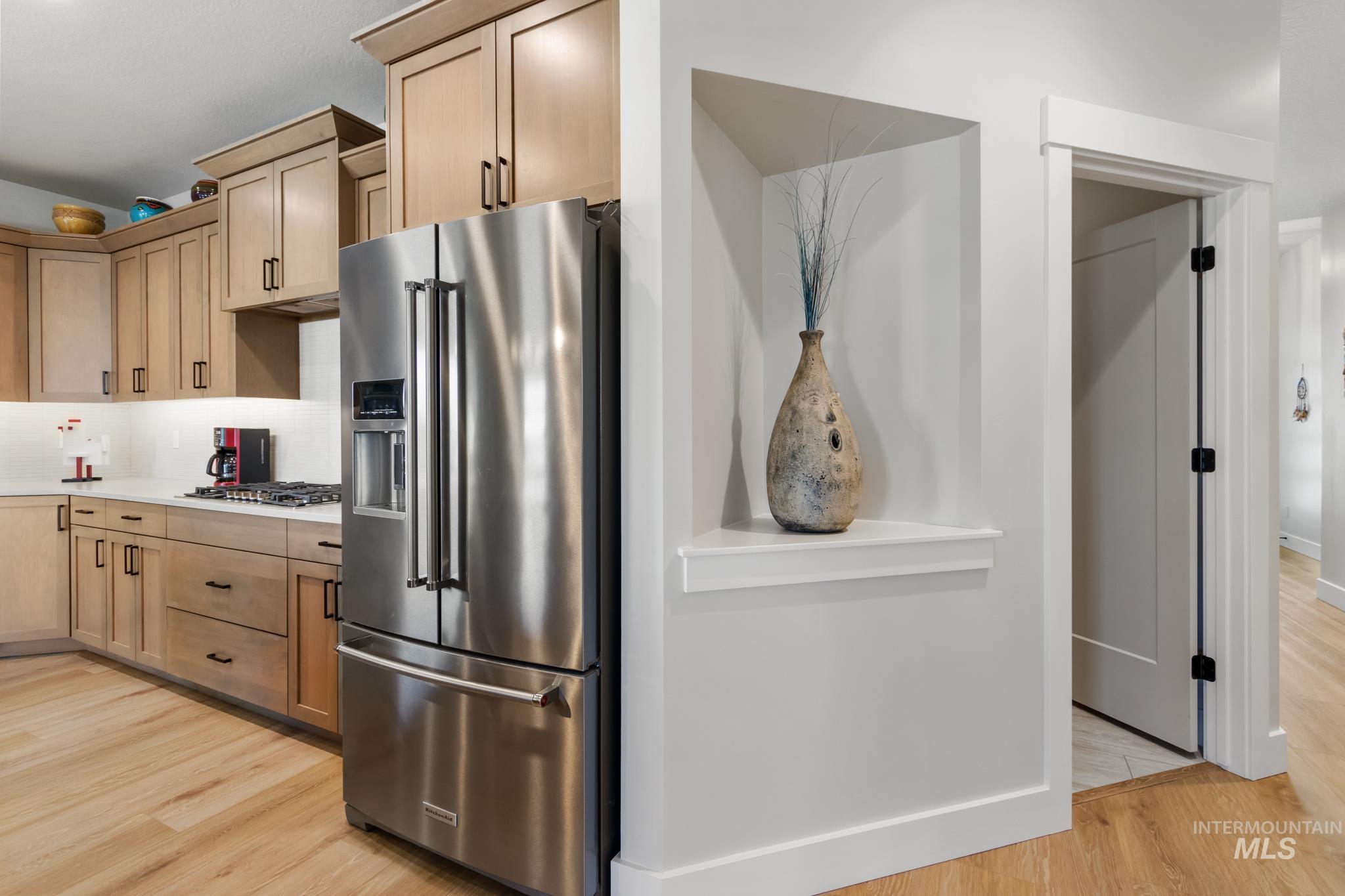 9864 West Aviara Street Star, ID 83669 - Photo 13 of 40 Kitchen featuring stainless steel appliances, light wood-style flooring, backsplash, and light wood finish cabinets
