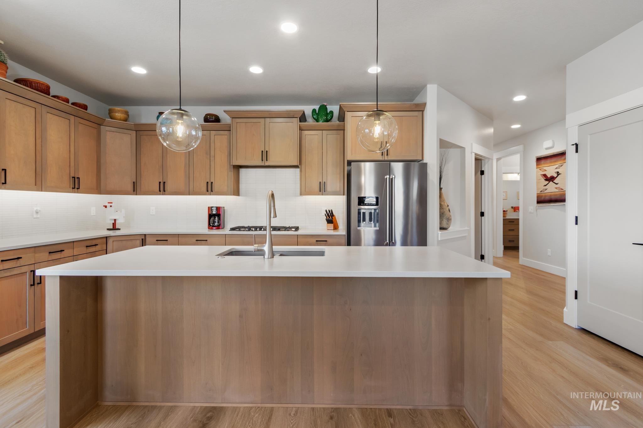 9864 West Aviara Street Star, ID 83669 - Photo 14 of 40 Kitchen with high end refrigerator, pendant lighting, tasteful backsplash, and light wood-style floors