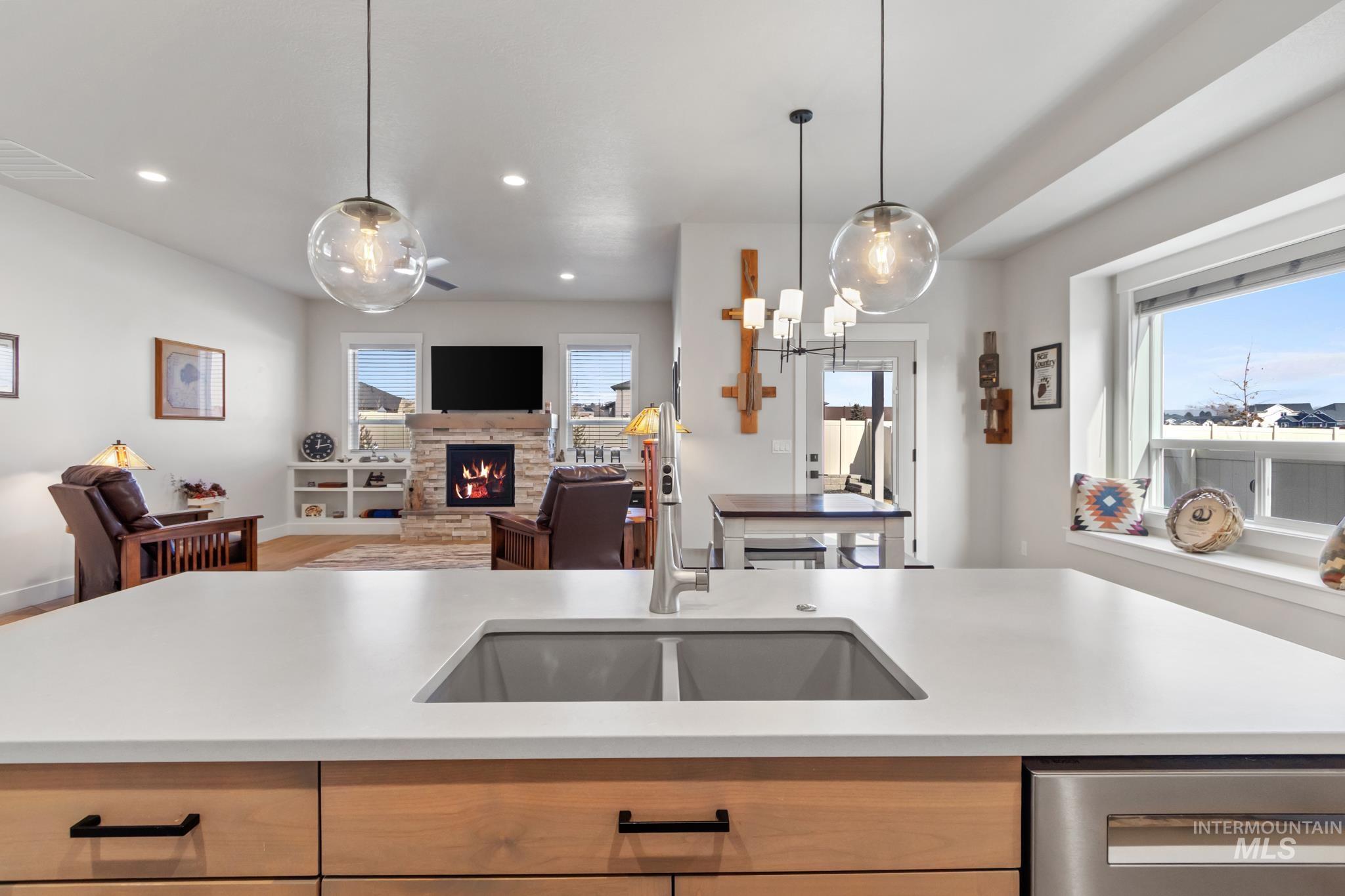 9864 West Aviara Street Star, ID 83669 - Photo 39 of 40 Kitchen with light wood finish cabinets, open floor plan, a stone fireplace, pendant lighting, and dishwasher