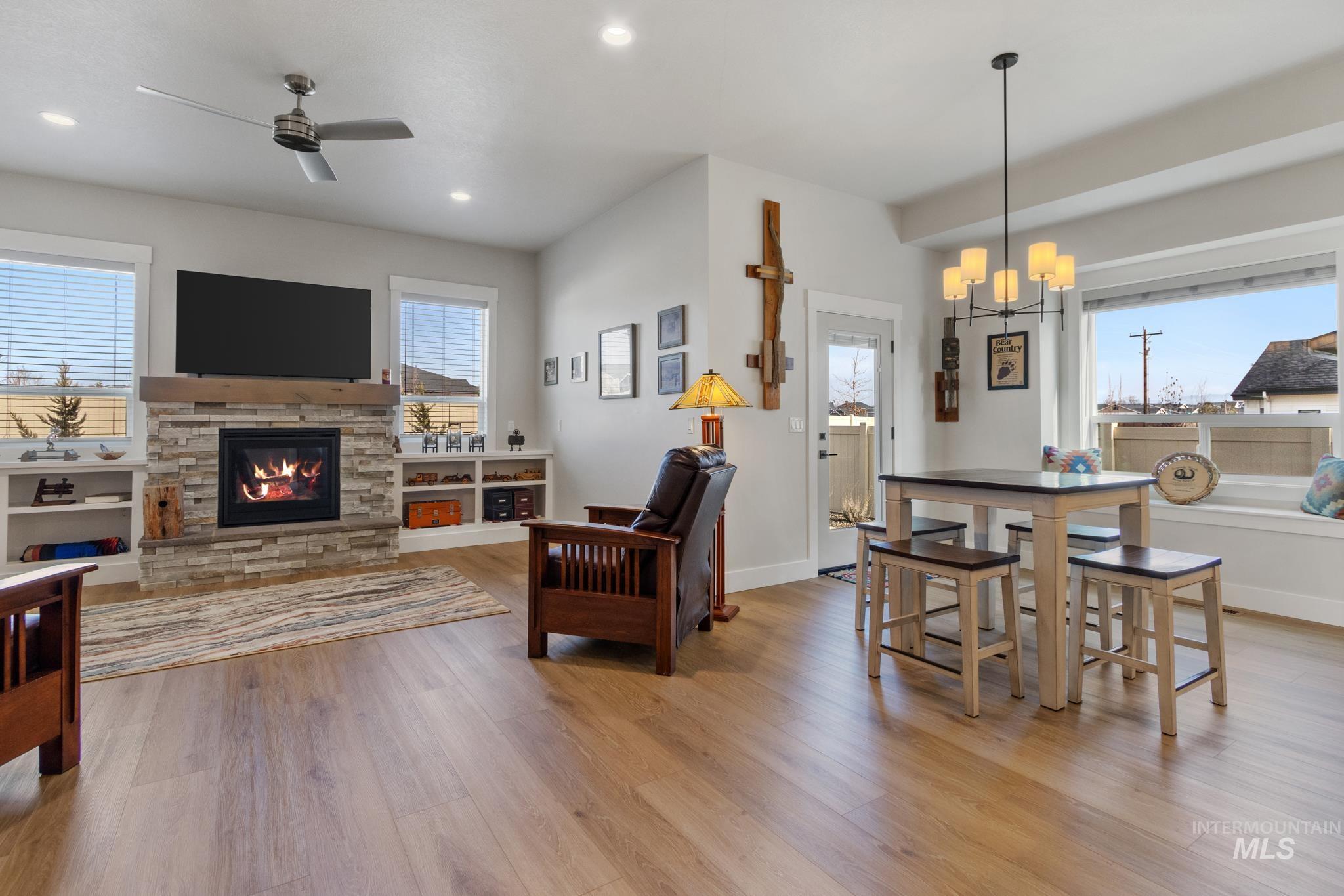9864 West Aviara Street Star, ID 83669 - Photo 20 of 40 Living area with a stone fireplace, light wood finished floors, hanging lights, and ceiling fan