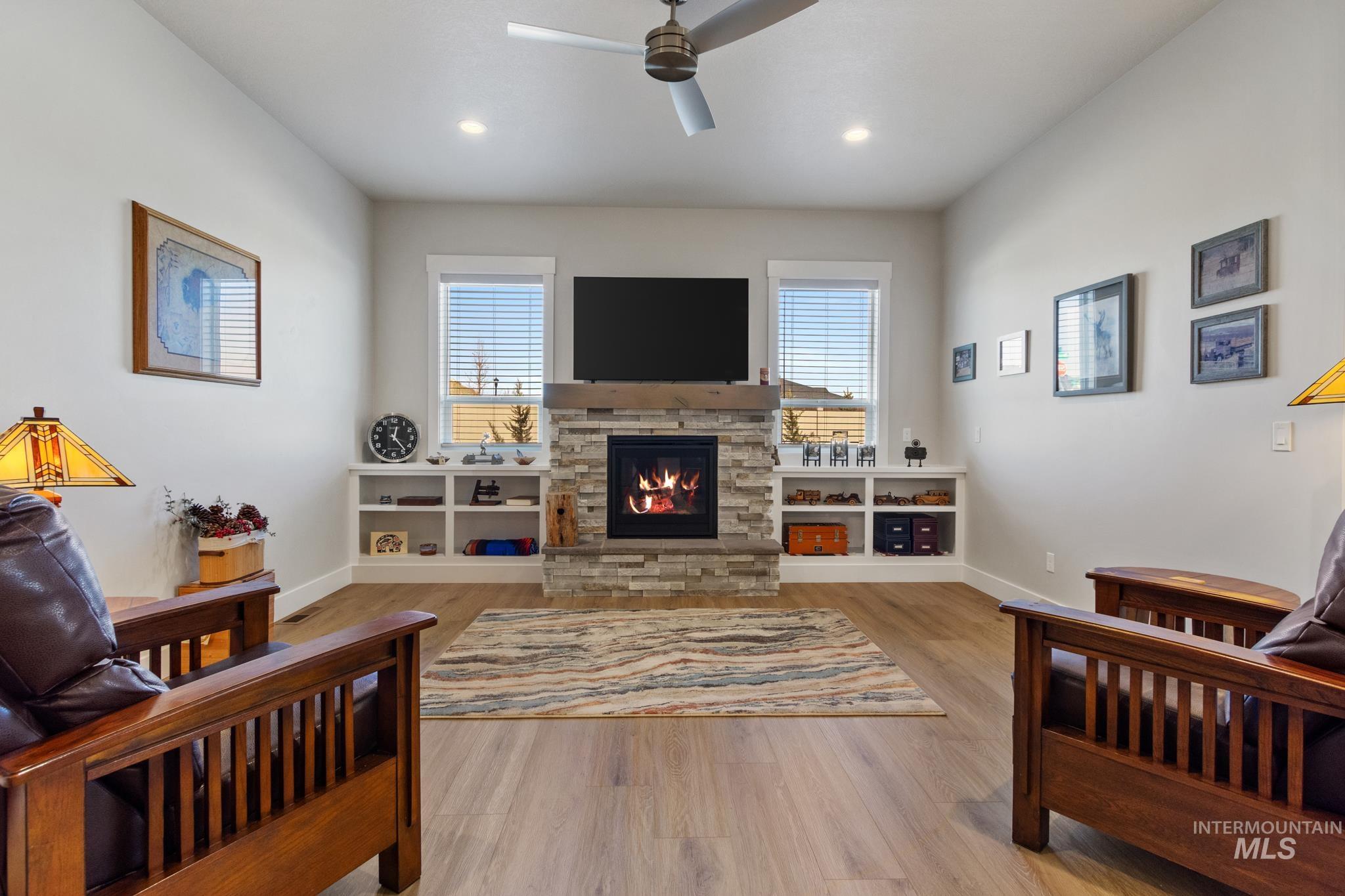 9864 West Aviara Street Star, ID 83669 - Photo 21 of 40 Living area with a stone fireplace, wood finished floors, ceiling fan, and recessed lighting