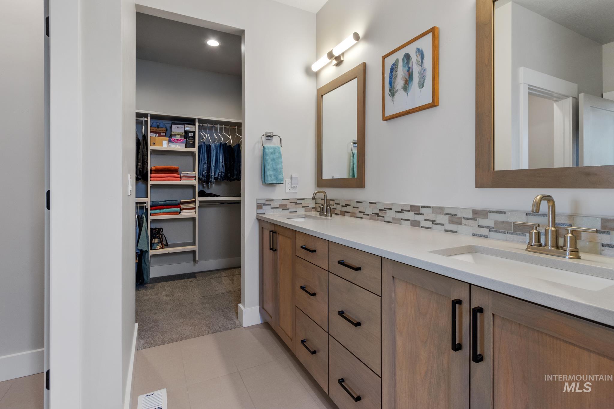 9864 West Aviara Street Star, ID 83669 - Photo 29 of 40 Bathroom featuring double vanity, a walk in closet, backsplash, and light tile patterned floors