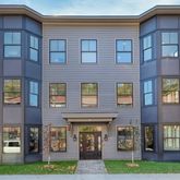 a front view of a brick building next to a yard