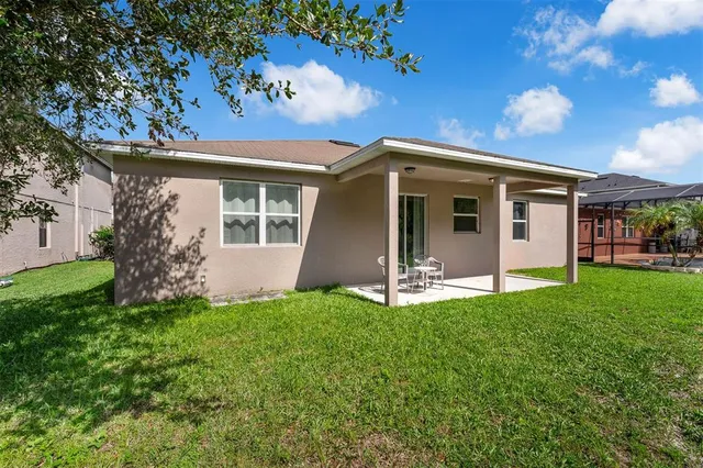 a view of a house with a yard patio and a tree
