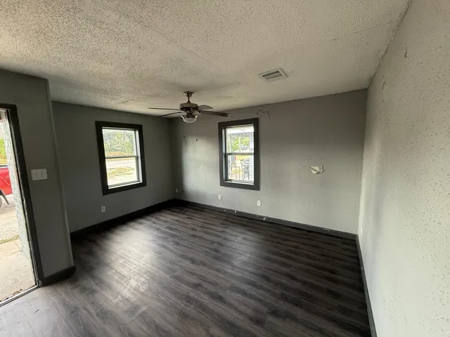 an empty room with wooden floor and windows