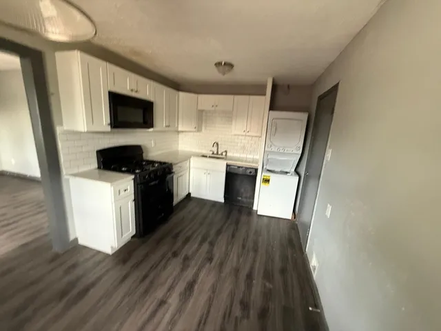 a kitchen with stainless steel appliances a refrigerator a sink a stove top oven a wooden floor and cabinets