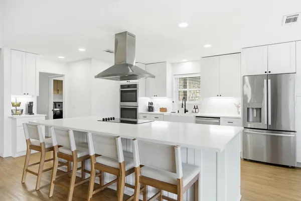 a kitchen with stainless steel appliances granite countertop a table chairs stove and refrigerator