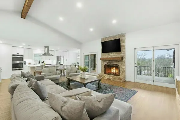 a living room with furniture kitchen view and large windows