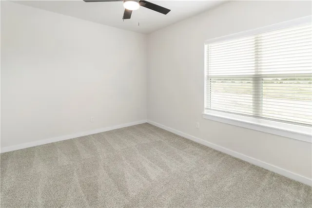 an empty room with a ceiling fan and a window