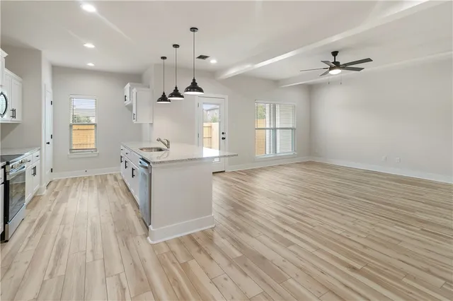 a kitchen with granite countertop stainless steel appliances a sink stove top oven and cabinets
