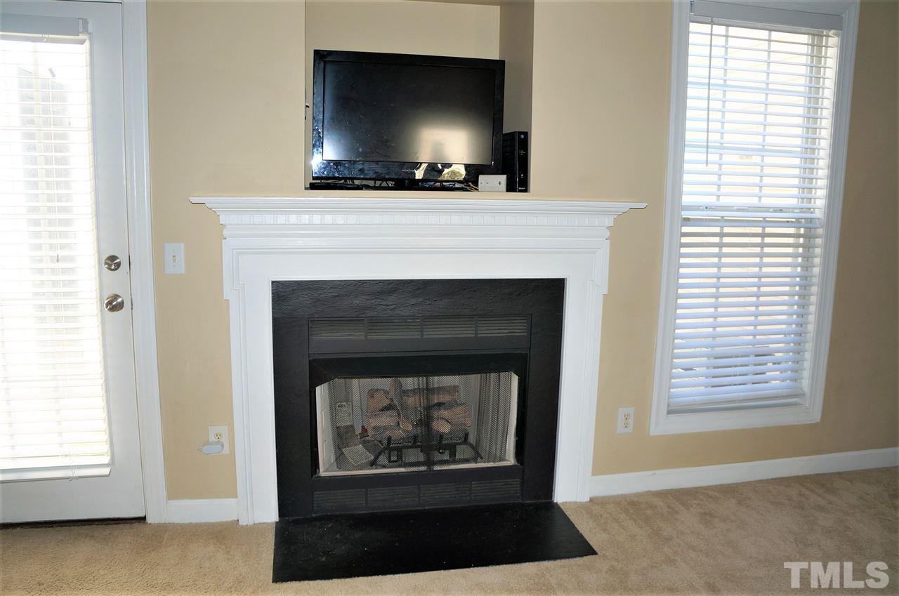 9204 Grassington Way Raleigh, NC 27615 - Photo 8 of 29 a living room with a fireplace and a flat screen tv